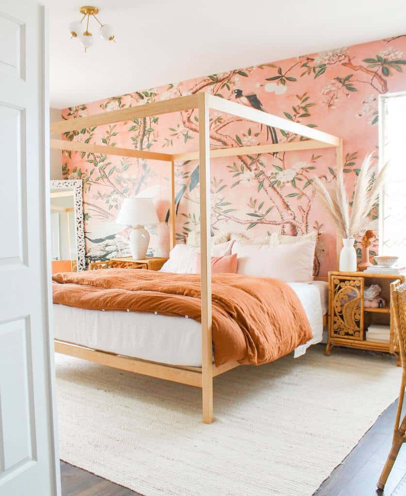 Pink floral wallpaper with a wooden four-poster bed and warm-toned bedding.