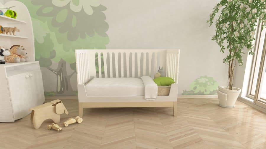 Nature-themed baby room with white crib, tree mural, and wooden toys, creating a playful forest vibe.