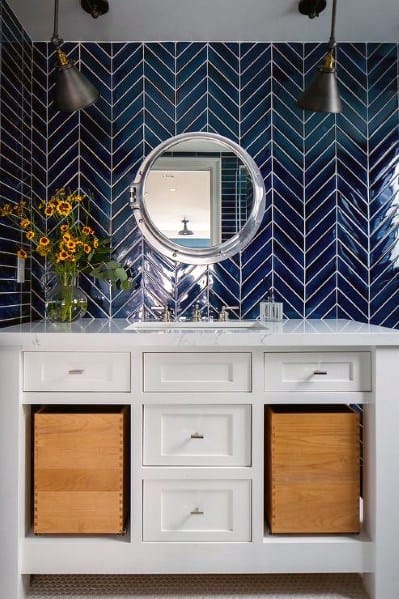 Small bathroom with navy blue herringbone tile backsplash and white vanity.