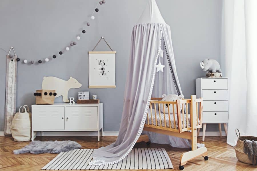 Minimalist baby room with a wooden crib, canopy, grey accents, and animal-themed decor.