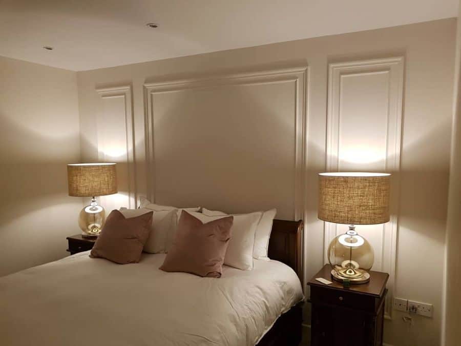 Neutral-colored bedroom with panel accent wall, soft lighting, and glass base lamps.