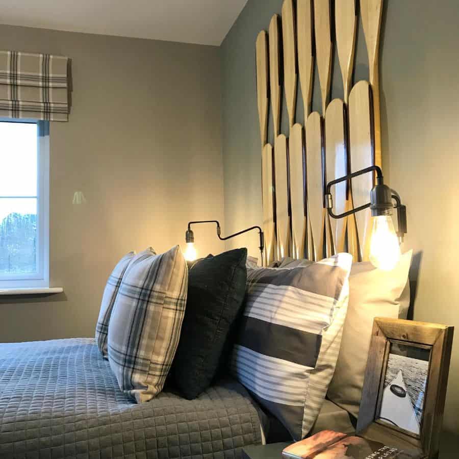 Boys' bedroom with oar wall art, plaid pillows, and industrial bedside lighting.