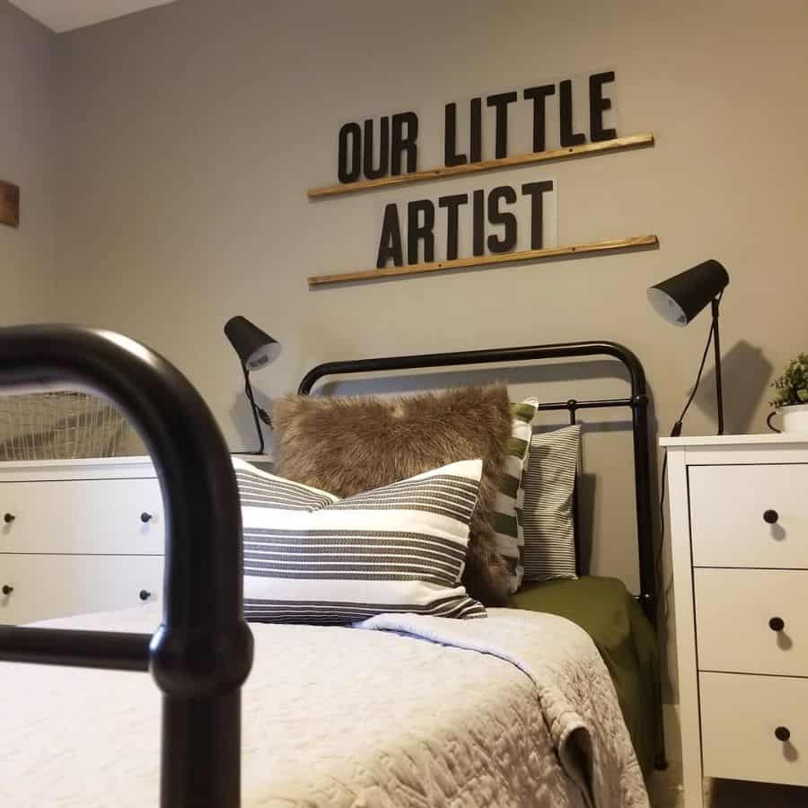 Small kids' bedroom with black metal bed, white cabinets, and "Our Little Artist" wall art.