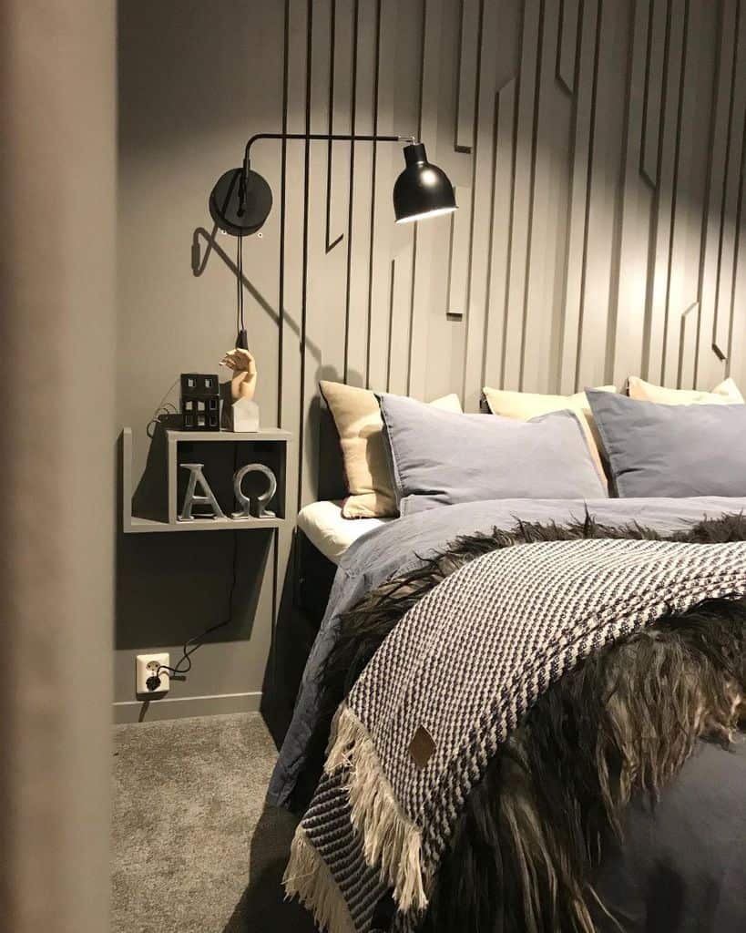 Modern bedroom with textured gray walls, black wall lamp, and cozy layered bedding.