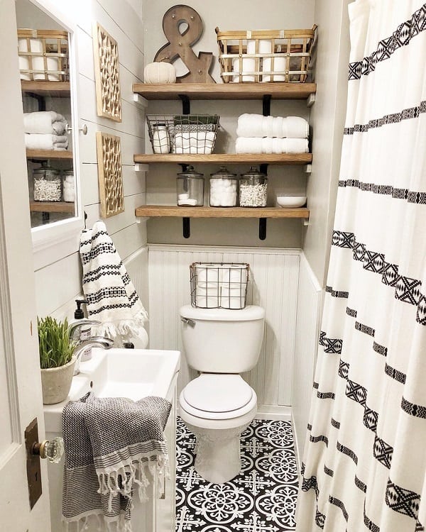 Cozy farmhouse bathroom with a patterned floor, shelves with baskets, striped towels, and a small sink