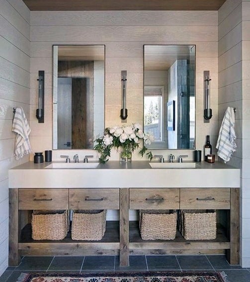 Dual vanity bathroom with rustic wood cabinets, wicker baskets, and modern sconces.