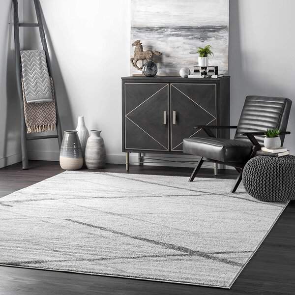 Modern living room with gray geometric rug, black leather chair, and decorative cabinet.