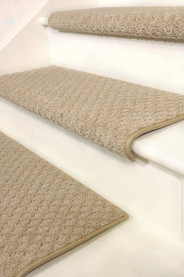 Beige carpet stair treads with a textured pattern on white wooden steps.