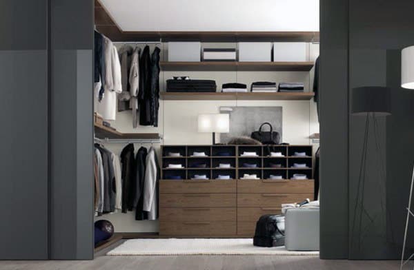 Modern walk-in closet with clothes, shelves, a dresser, and a lamp, featuring neutral tones and organized space