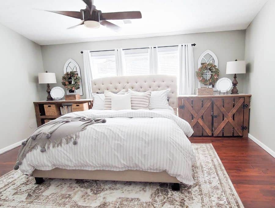 Bright bedroom with rustic wood accents, tufted headboard, and ceiling fan.