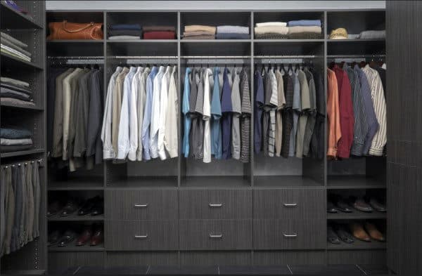 Organized closet with shirts, pants, and folded clothes on shelves, drawers below, and shoes neatly arranged