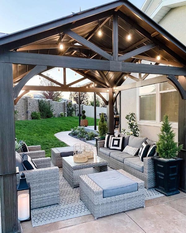 Charming outdoor gazebo with string lights, cushioned wicker furniture, and a patterned rug, creating a cozy and stylish retreat