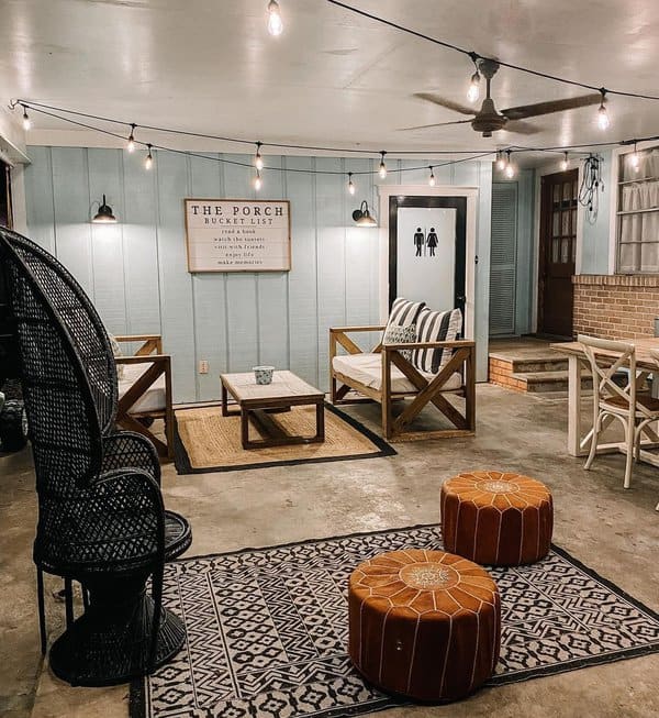 Charming porch setup featuring cozy string lights, rustic wooden furniture, Moroccan-style poufs, patterned rugs, and wall-mounted lighting for a warm and inviting atmosphere