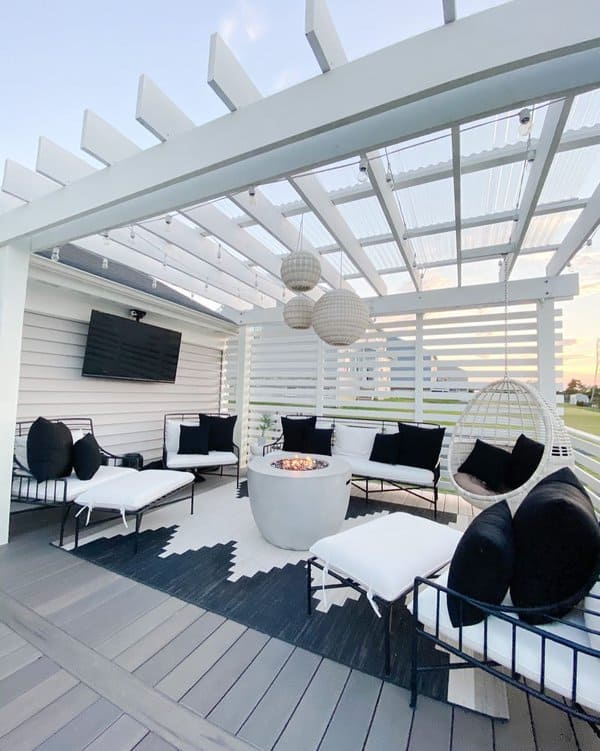 Stylish outdoor living area with a white pergola, sleek black and white furniture, and a central firepit for cozy evenings