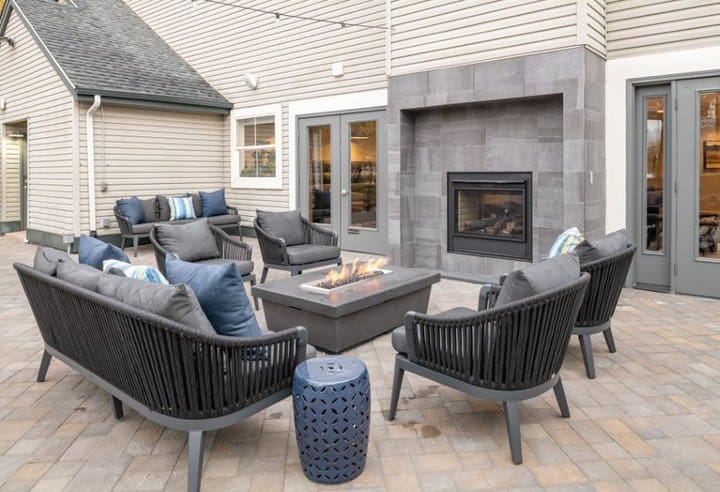 Chic outdoor patio with sleek black seating, a modern firepit, and a built-in fireplace for a stylish and cozy gathering space