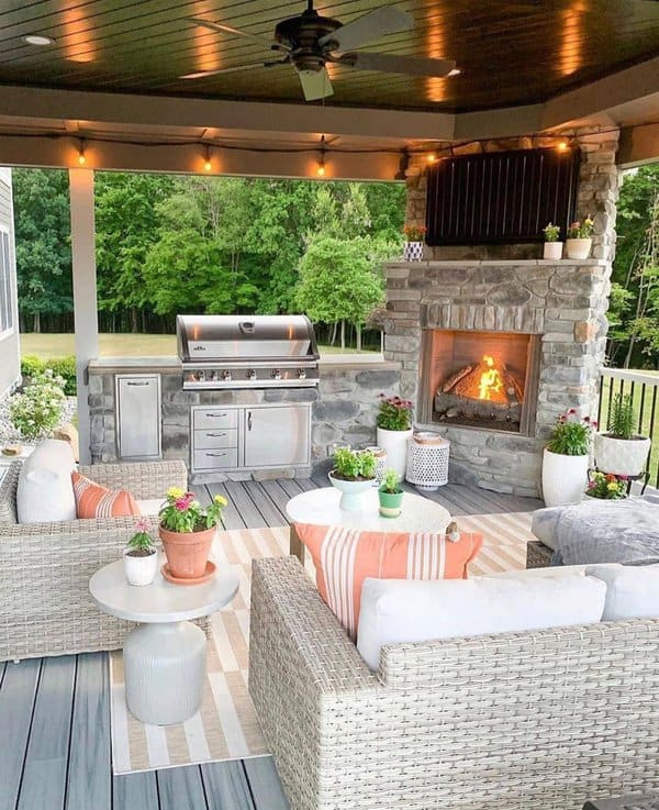 Chic outdoor living space with a stone fireplace, built-in grill, and cozy wicker seating for perfect entertaining vibes