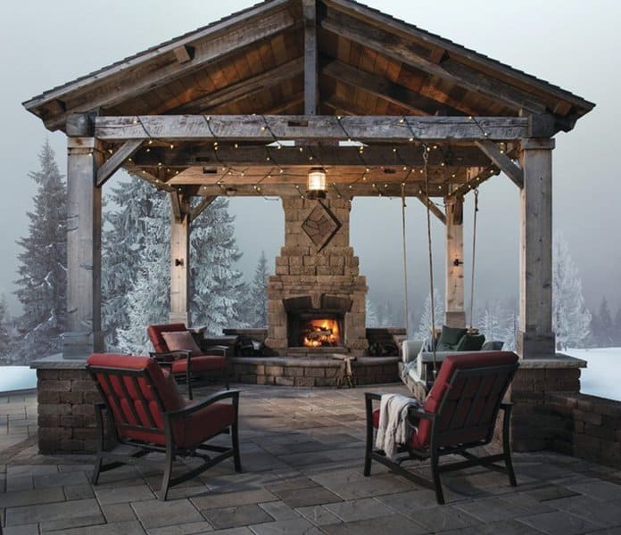 Cozy rustic pavilion with a stone fireplace, wooden beams, and inviting red-cushioned seating for a warm winter retreat