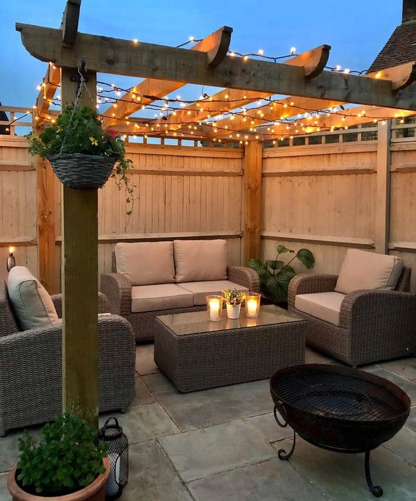 Cozy patio setting with wicker furniture, a wooden pergola adorned with string lights, and soft candlelight ambiance, creating the perfect space for intimate gatherings