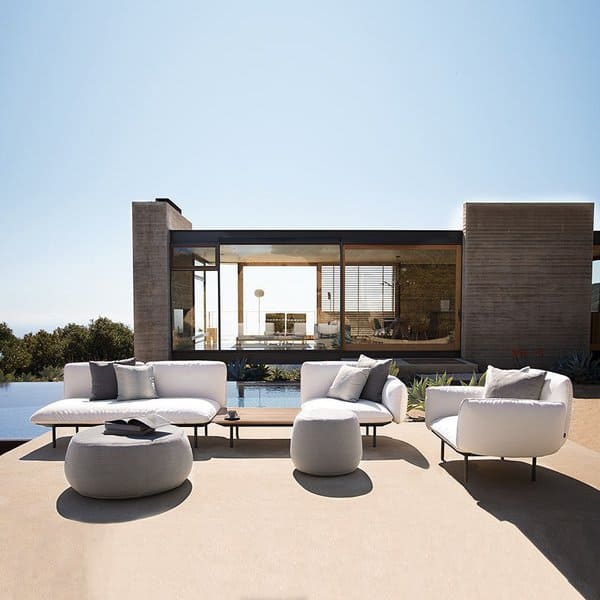 Modern outdoor seating area with plush white furniture, a sleek pool, and a glass-walled home as the perfect backdrop