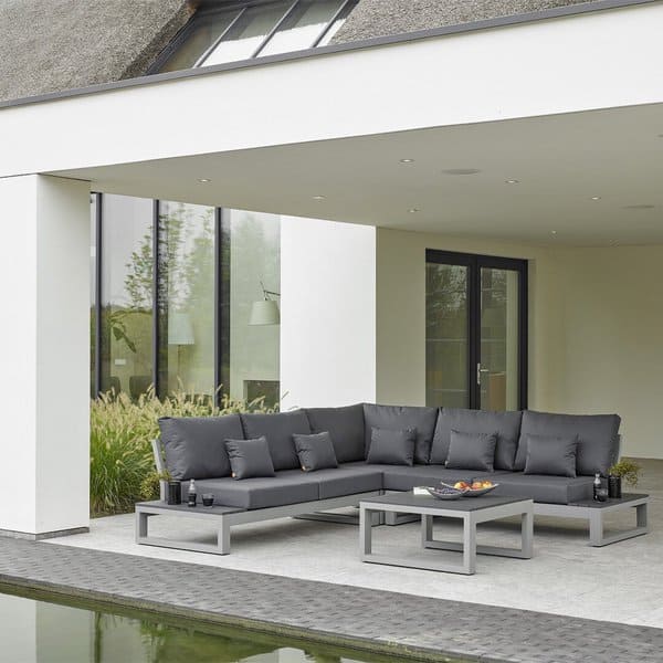 Contemporary outdoor sectional sofa in sleek gray with a minimalist table, set under a modern covered patio by a reflective pond