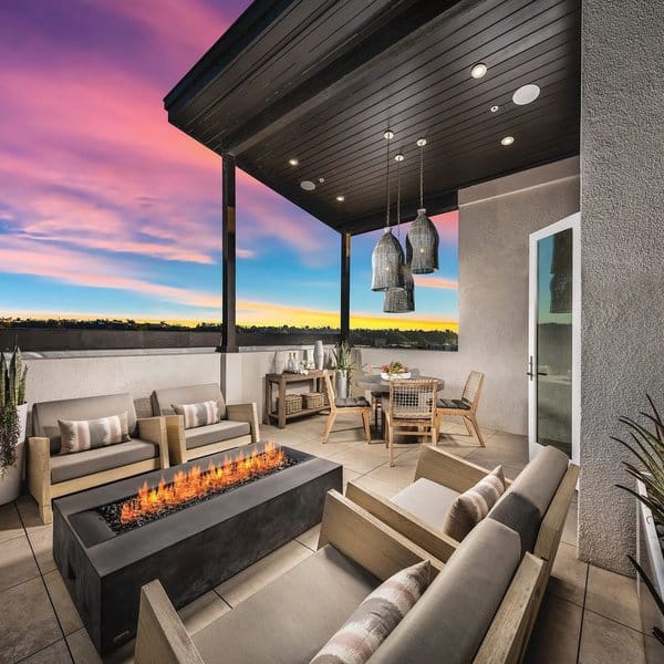 Luxury rooftop retreat with a sleek firepit, cozy seating, pendant lighting, and a stunning sunset view for evening gatherings