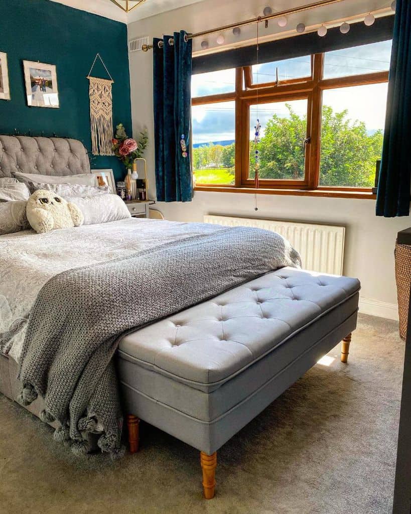 blue accent wall in small boho bedroom with ottoman 