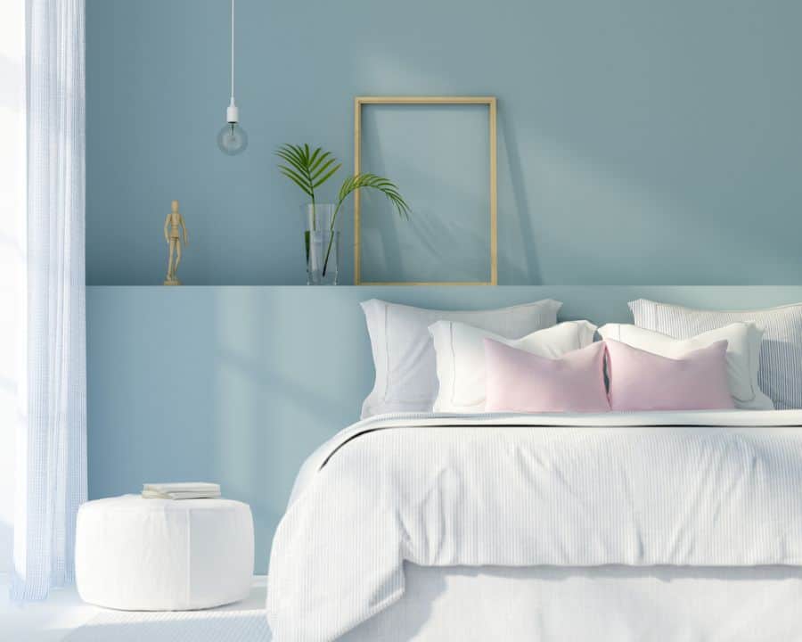 Pastel blue bedroom with white bedding, pink pillows, and minimal wall decor.