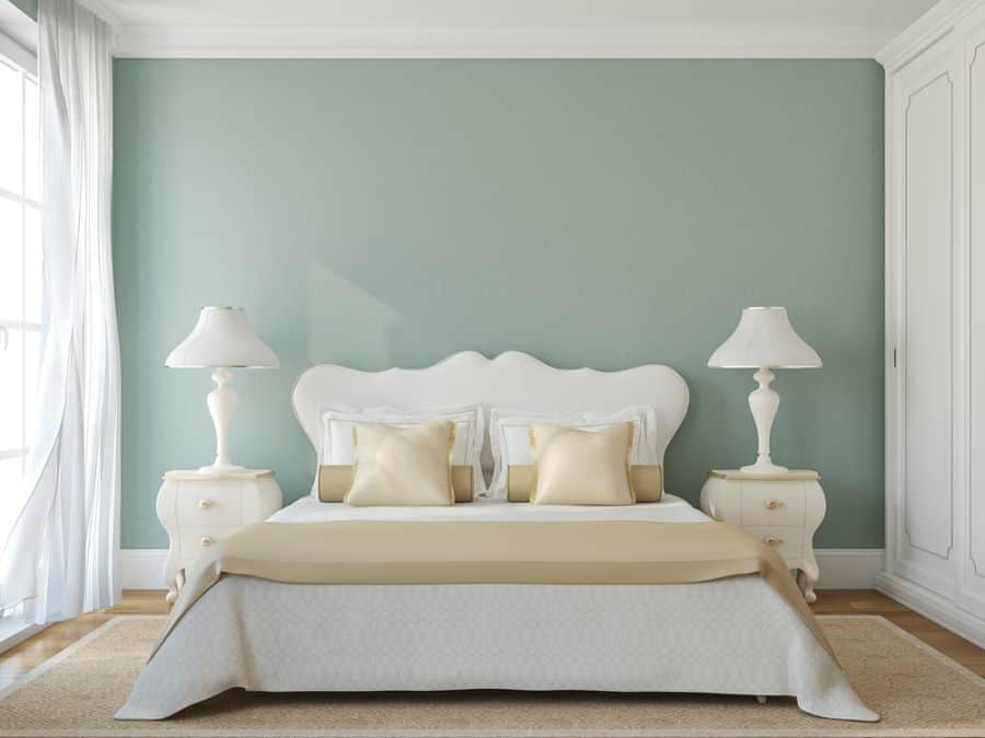 Pastel blue bedroom with white bed and bedside tables.