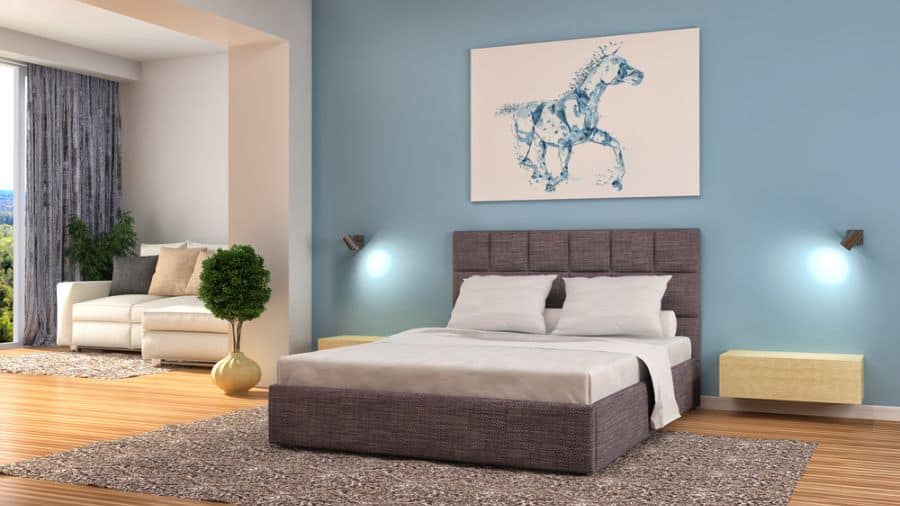 Pastel blue bedroom with horse artwork above upholstered bed and cozy area rug.