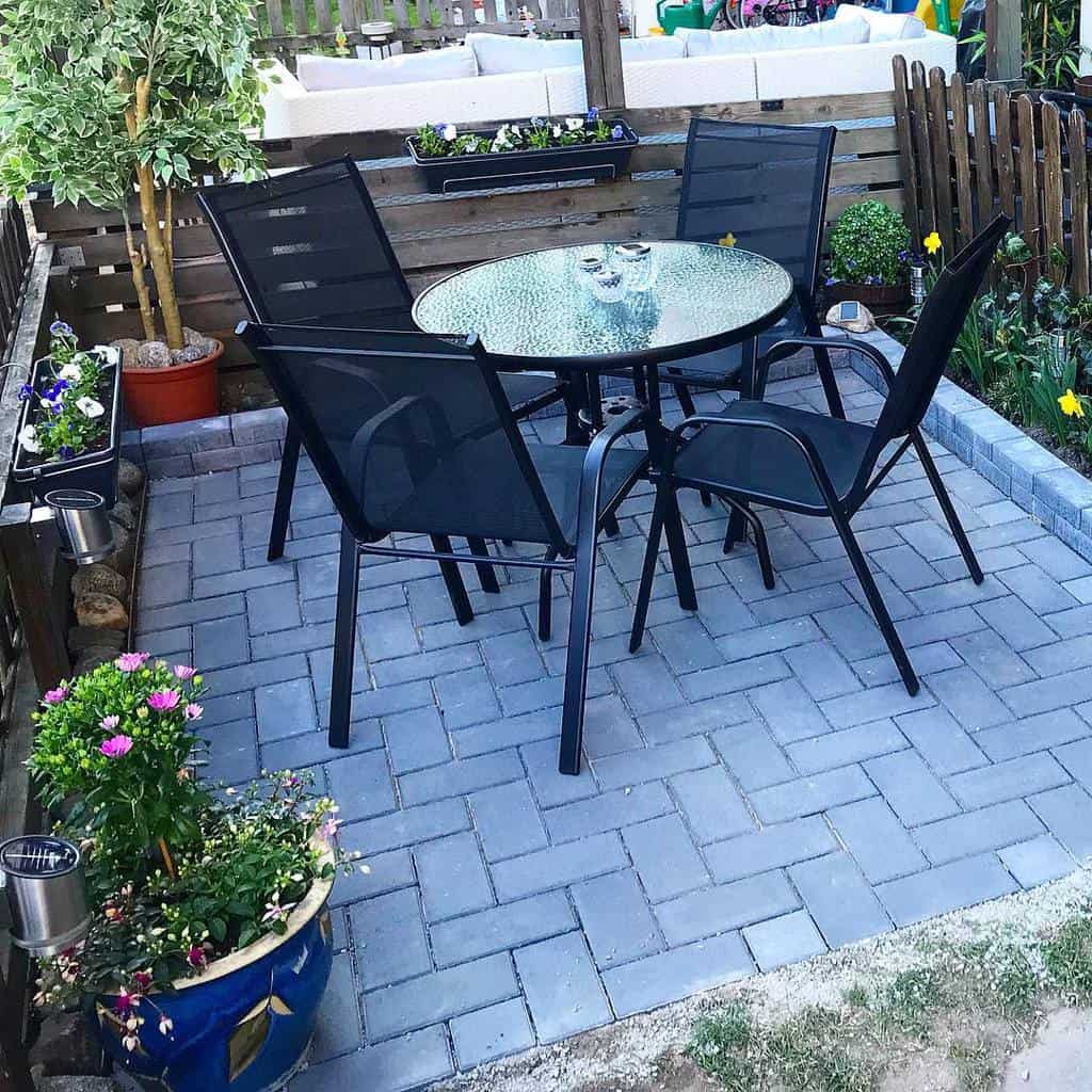 gray paver patio glass table black chairs planter garden 