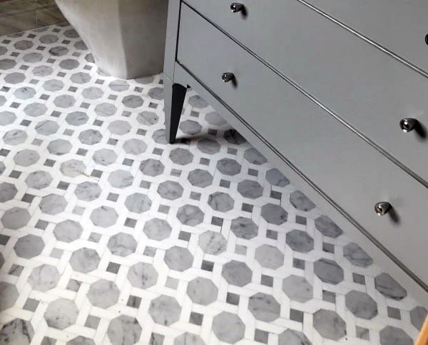 Gray and white geometric patterned bathroom floor tiles with gray vanity.