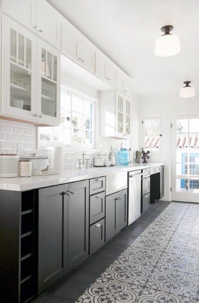 Black and white kitchen with patterned tile flooring, glass cabinet doors, and subway tile backsplash.