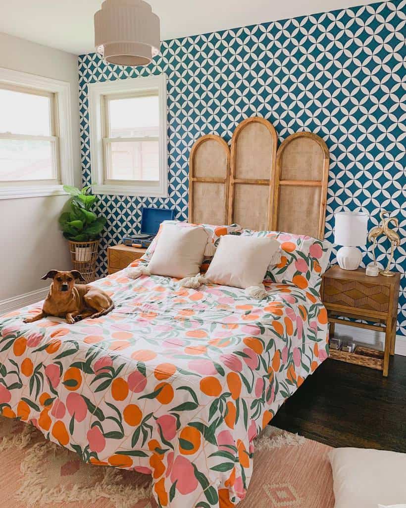 Bedroom with geometric blue wallpaper, colorful floral bedspread, and rattan headboard.