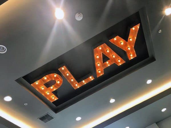 Ceiling with illuminated "PLAY" sign in bold, vintage-style letters