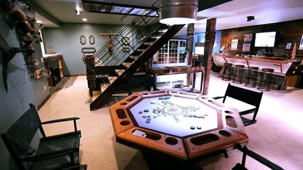 Rustic man cave with a custom poker table, bar area, and industrial-style staircase.