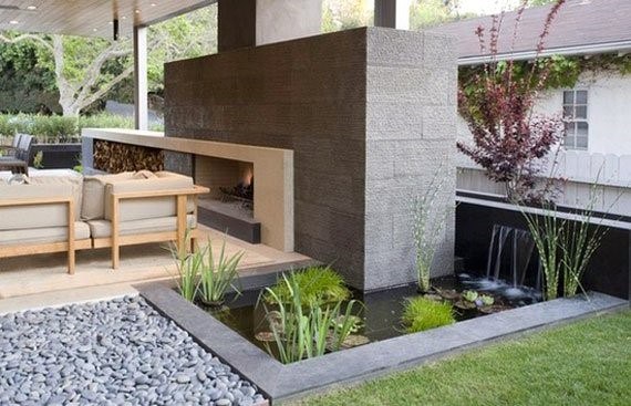 Sleek tiled pond with water plants and a small waterfall, adjacent to a cozy outdoor seating area.