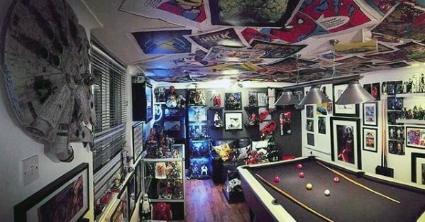 Room with comic-themed decor, pool table, Star Wars model on wall, and action figures on shelves