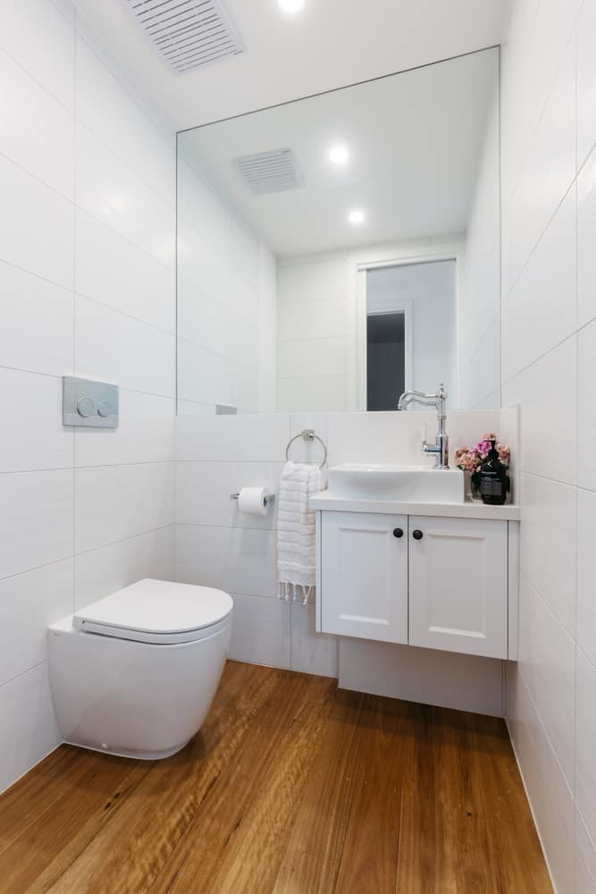 simple white powder room wood flooring white vanity 