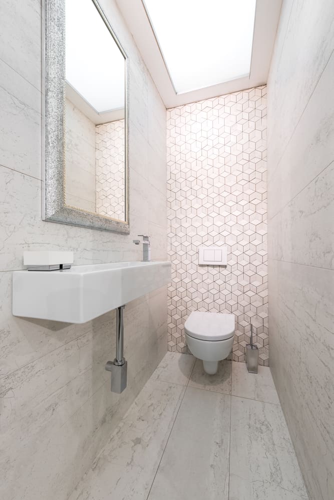 Minimalist bathroom with wall-mounted sink and toilet, light tiles, and geometric accent wall