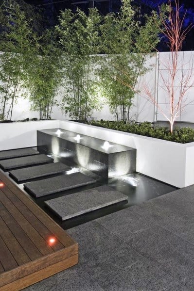 Floating stone steps over a sleek pond with modern water features, surrounded by bamboo and minimal landscaping.