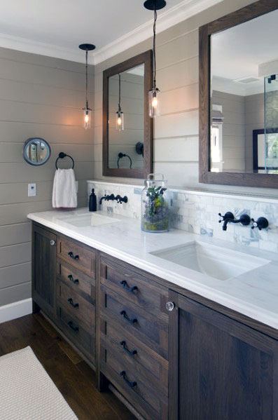 Bathroom with marble tile backsplash, double wood vanity, and industrial pendant lights.