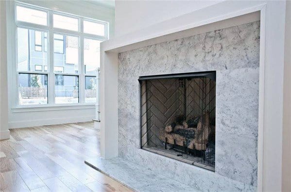 Bright living room with a white marble fireplace featuring a herringbone brick interior.