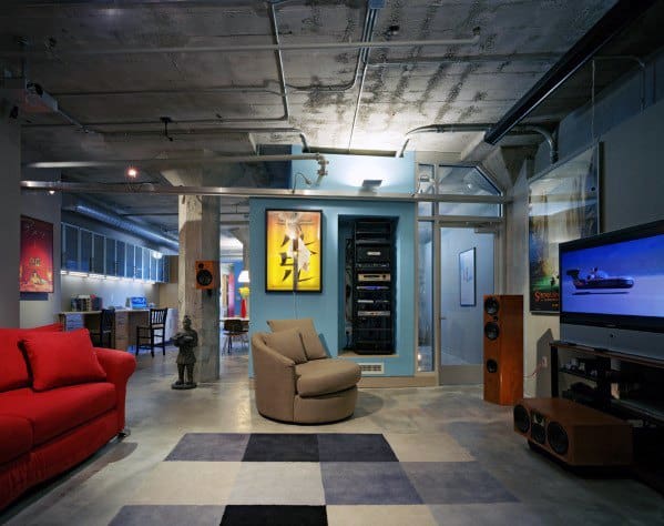 Industrial-style man cave with exposed ceilings, red sofa, entertainment system, and modern decor elements.