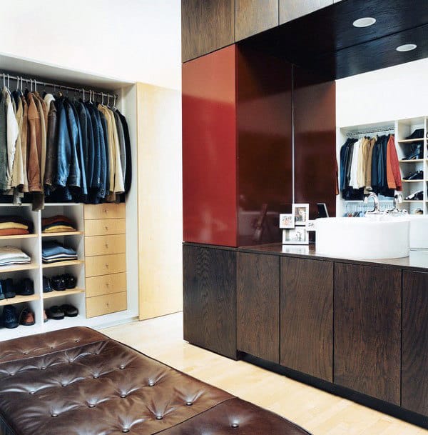 Modern closet with open storage for clothes and shoes, a central bench, and a sink with dark wood cabinetry