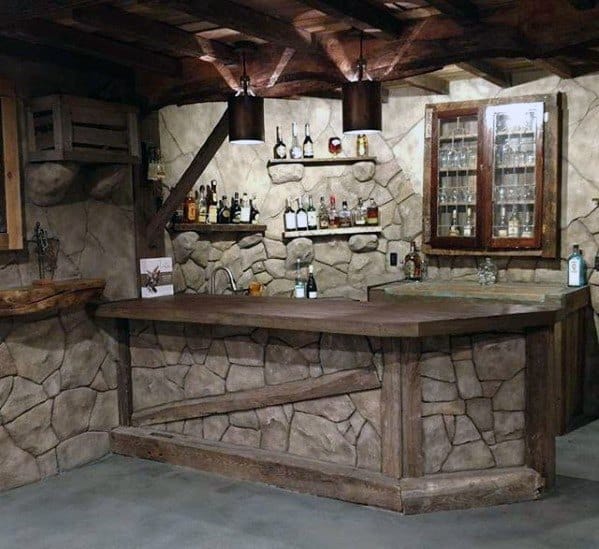 Rustic stone bar with wood accents, shelves for liquor display, and warm overhead lighting.