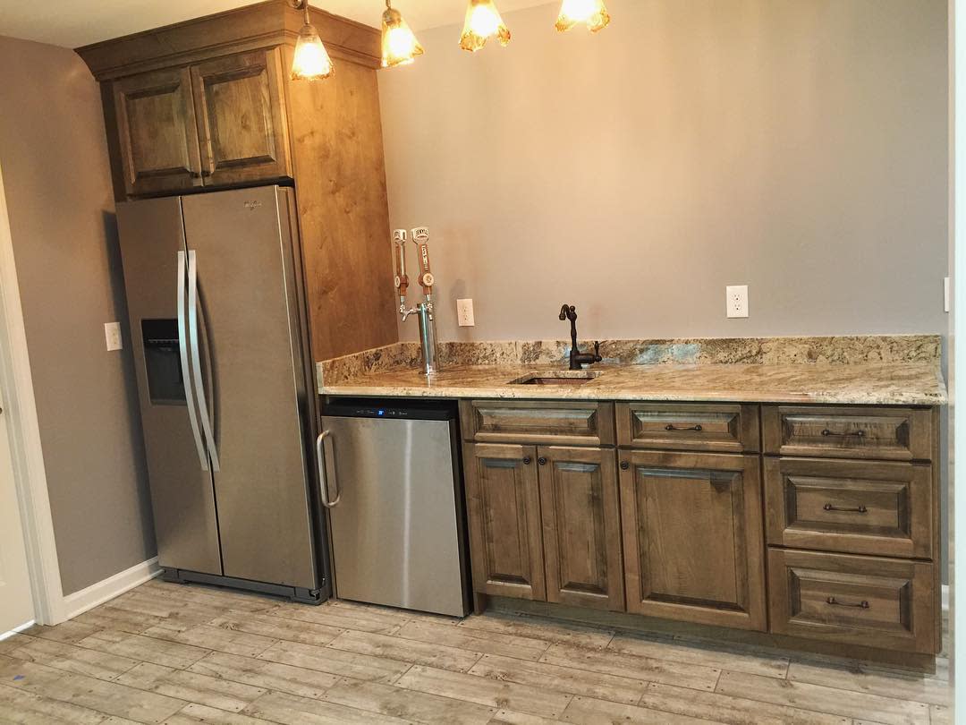 Rustic basement kitchen with wood cabinets, granite countertops, and modern fridge.