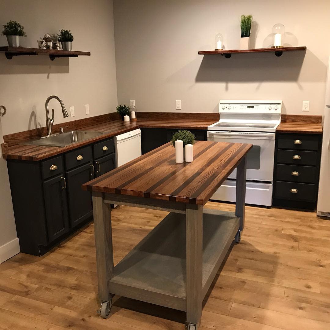 Simple rustic kitchen with dark cabinets, wood countertops, and small center island.