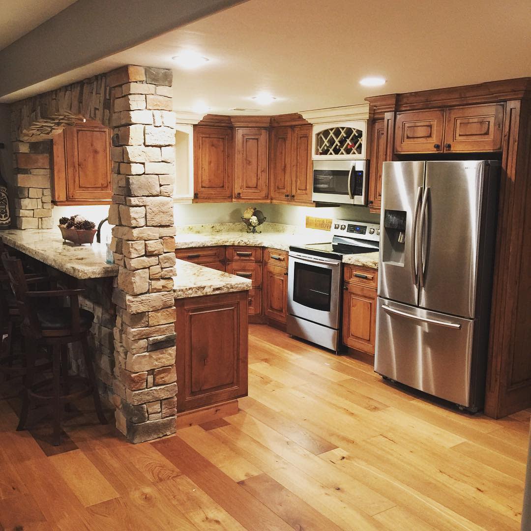 Rustic kitchen with stone accents, wood floorboards, and light wood cabinets.