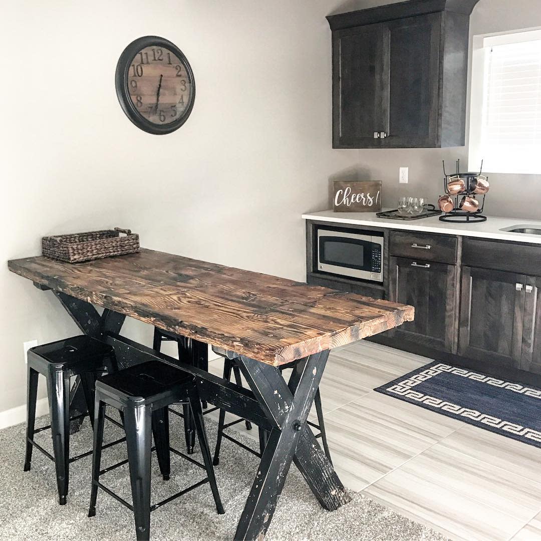 Rustic kitchen with dark wood cabinets, wooden table, and industrial bar stools.