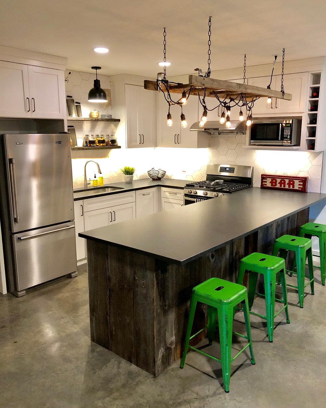 Modern kitchen with rustic island, green stools, and industrial light fixture.